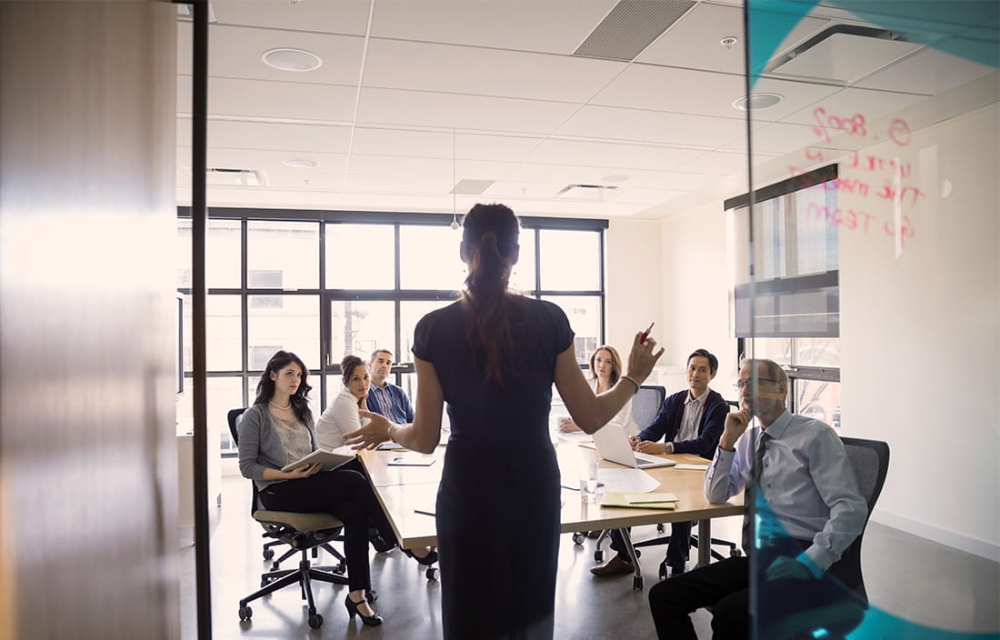 A business woman presenting in a conference room on how to increase operating margins.