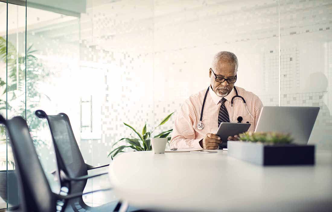 Doctor wearing a stethoscope while reviewing information on a tablet.