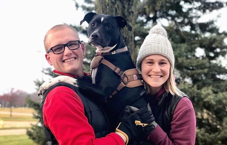 Man and woman holding a dog together.