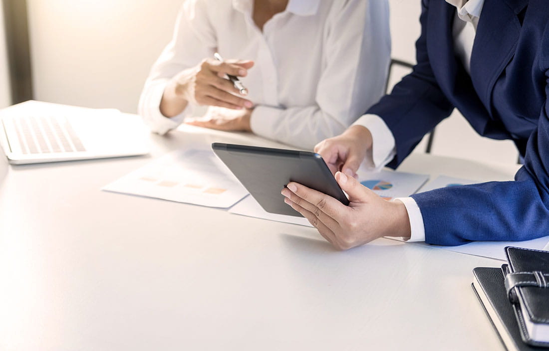 Man and a woman sitting at a table looking at an iPad