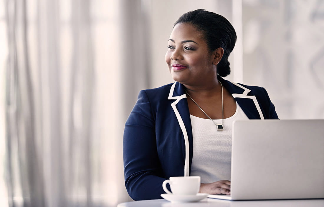 A woman sitting at a table, typing on her laptop