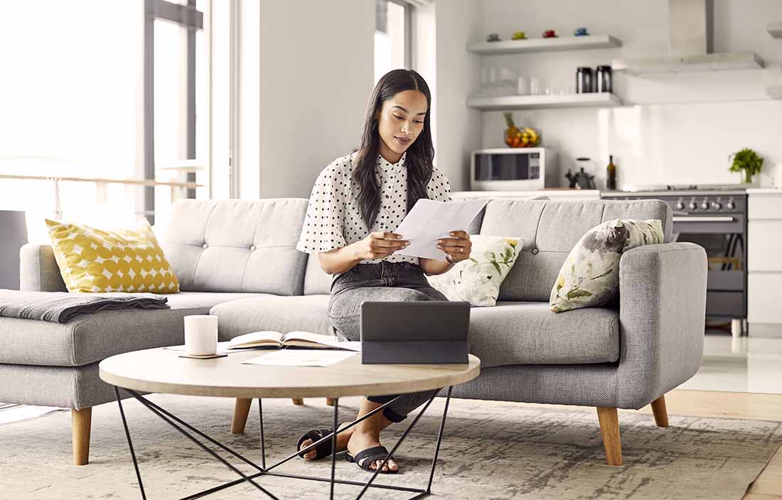 Woman sitting on a couch looking at some papers