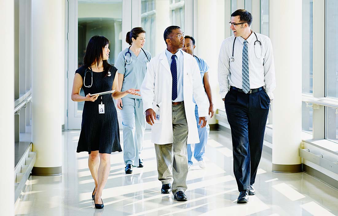 Group of doctors and nurses walking down hospital hallway.