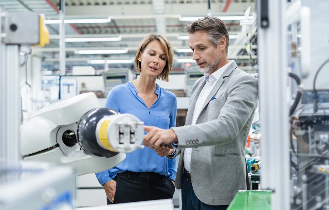 Professionals in the plastics industry inspecting a factory machine.