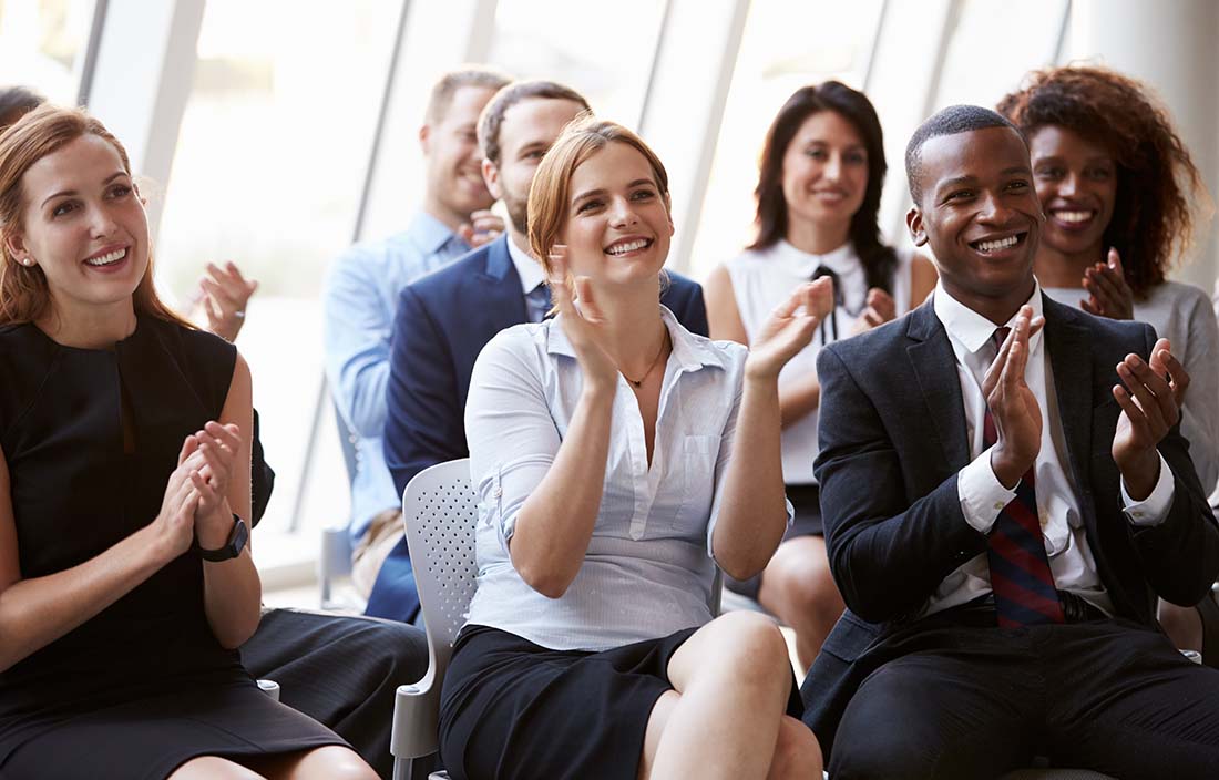 Education professionals attending a conference and clapping for a speaker.