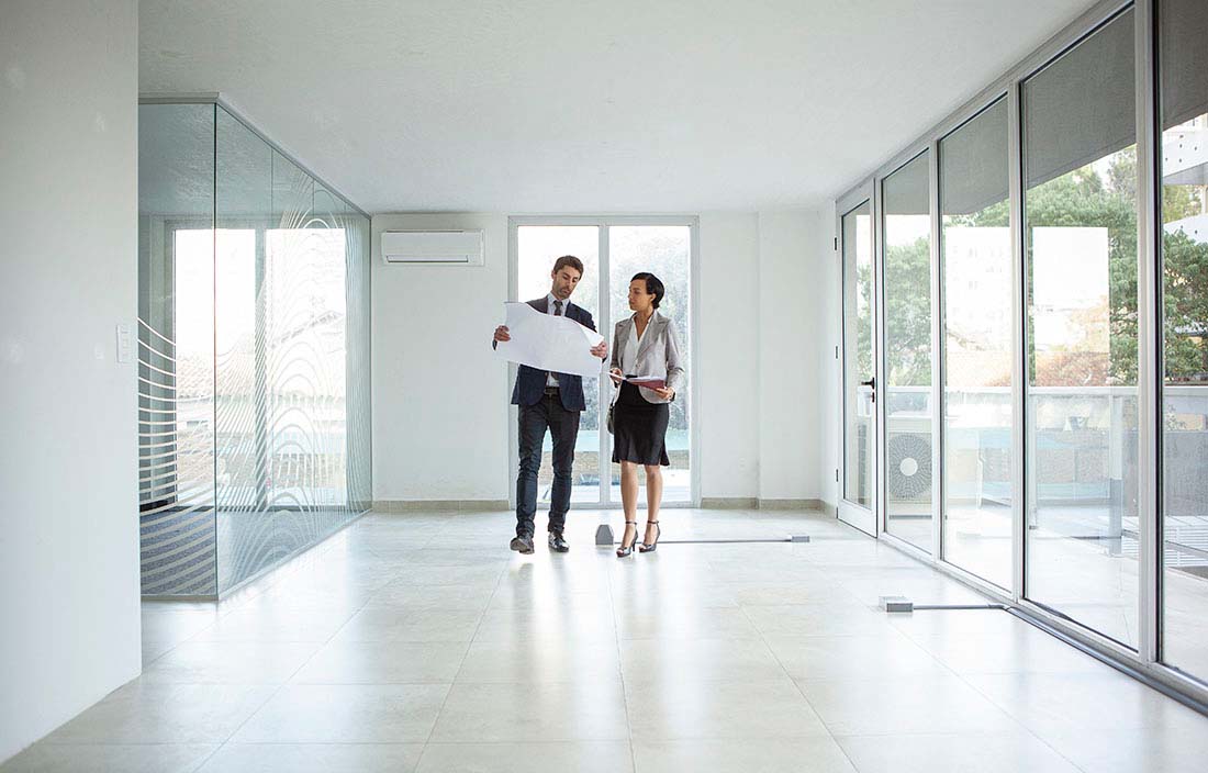 Real estate professionals in a modern office space reviewing blueprints.