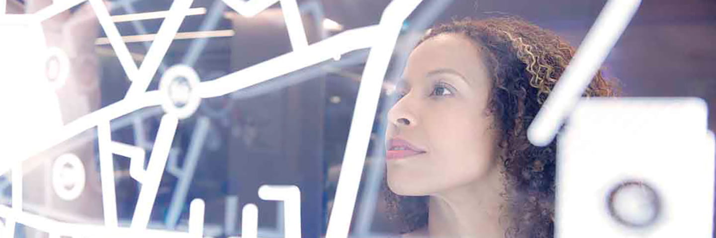 Business professional looking at information on a clear glass board.