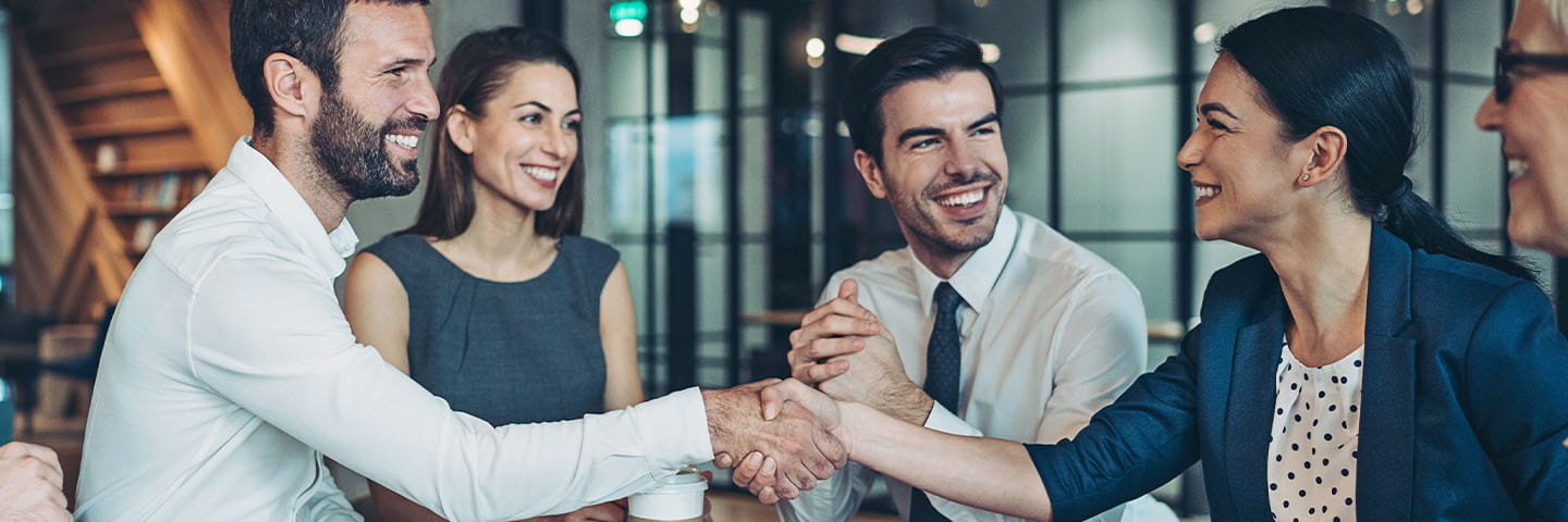 Business professionals shaking hands together.