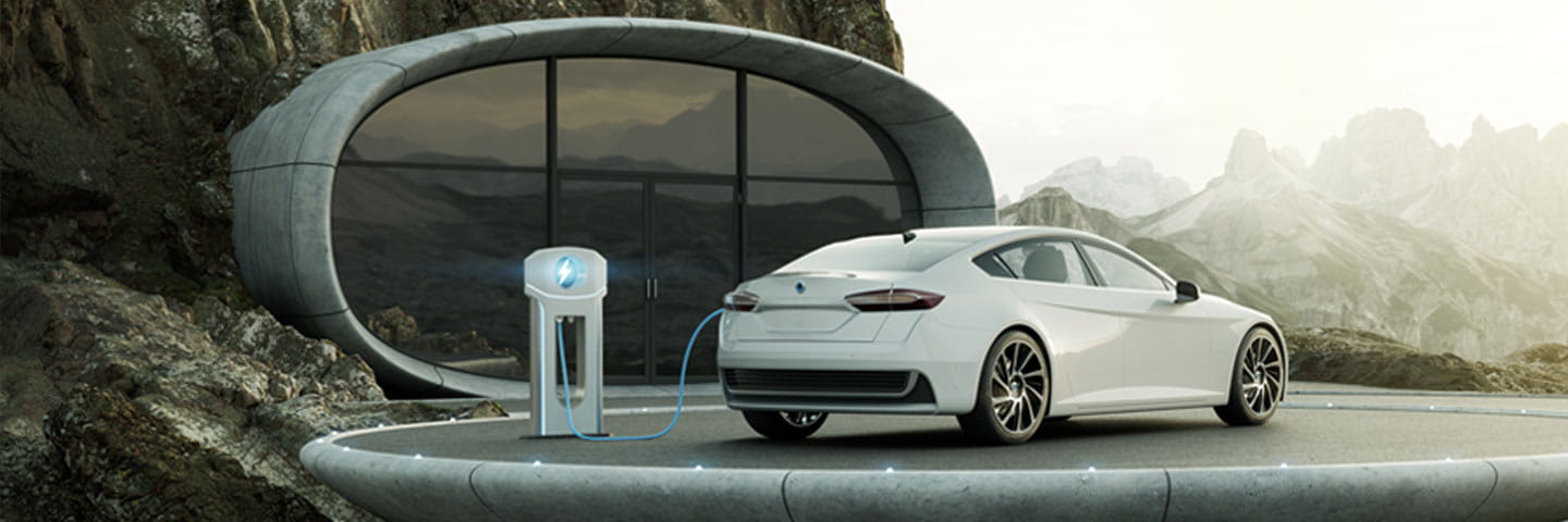 Electrical vehicle charging in a driveway with a mountain landscape in the background.