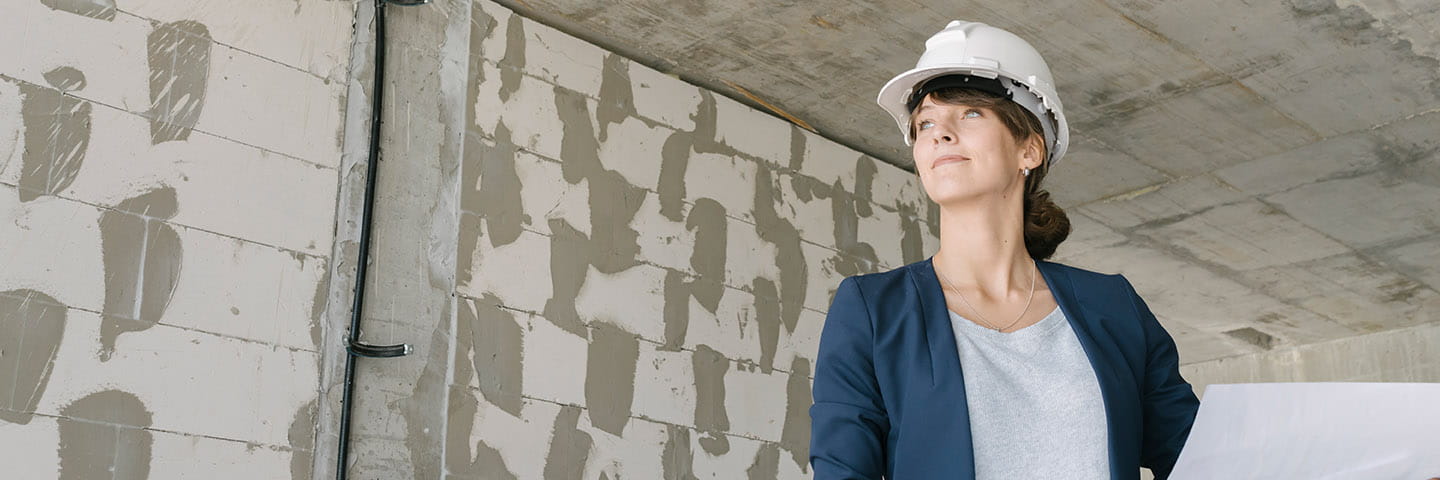 Construction professional in a hard hat looking at blueprints.