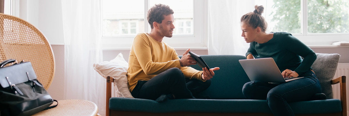 Couple sitting on couch and looking over finances.