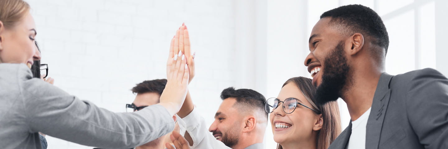 Group of coworkers high fiving and smiling.