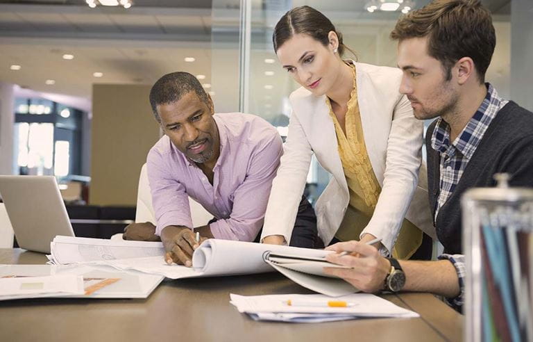 Image of three business people reviewing documents in an office.