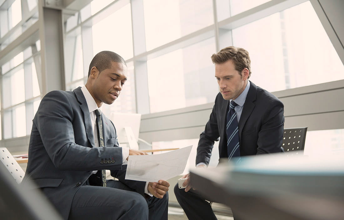 Two men sitting discussing reports