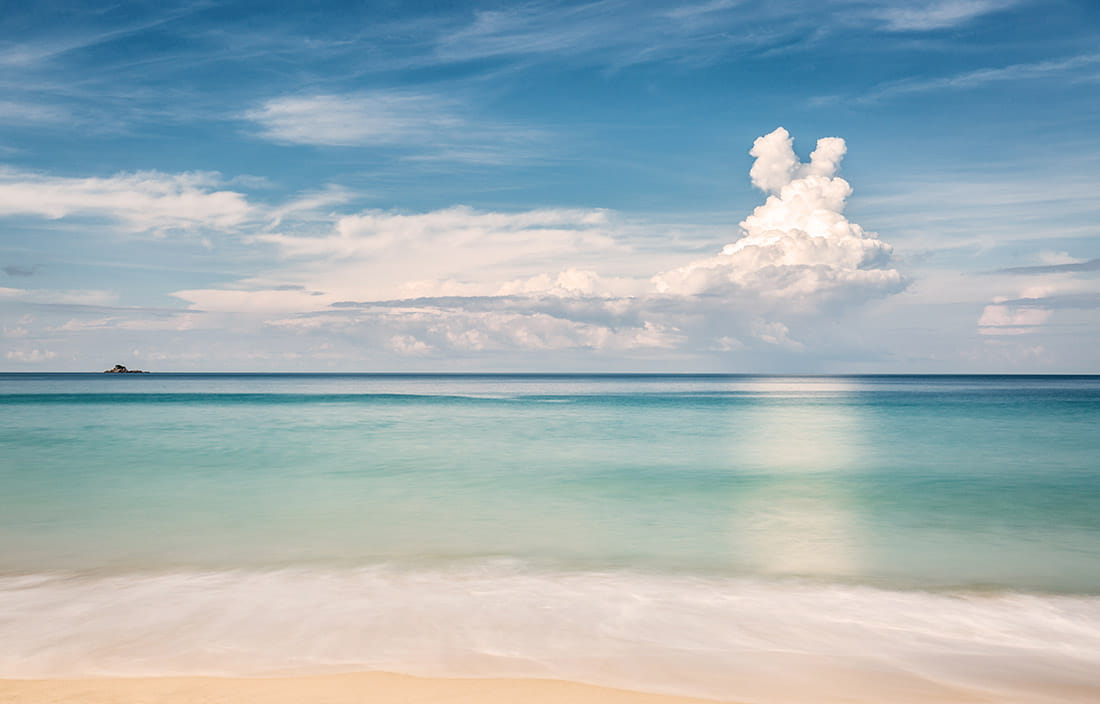 View of a beach and ocean horizon during the day.