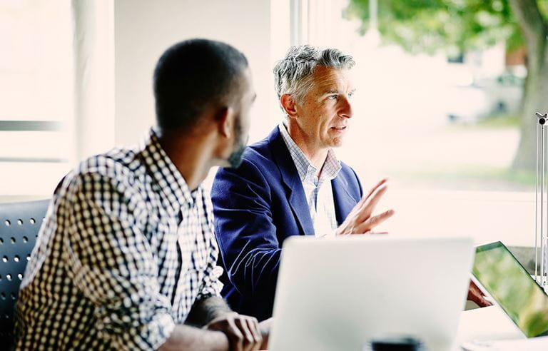 Two male businessmen talking with their investment banker.