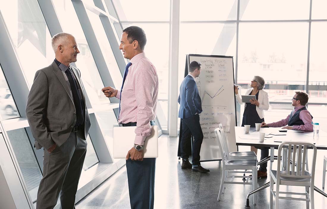 Business colleagues in a conference room sharing the four tips to improve sales forecasting on a whiteboard. 