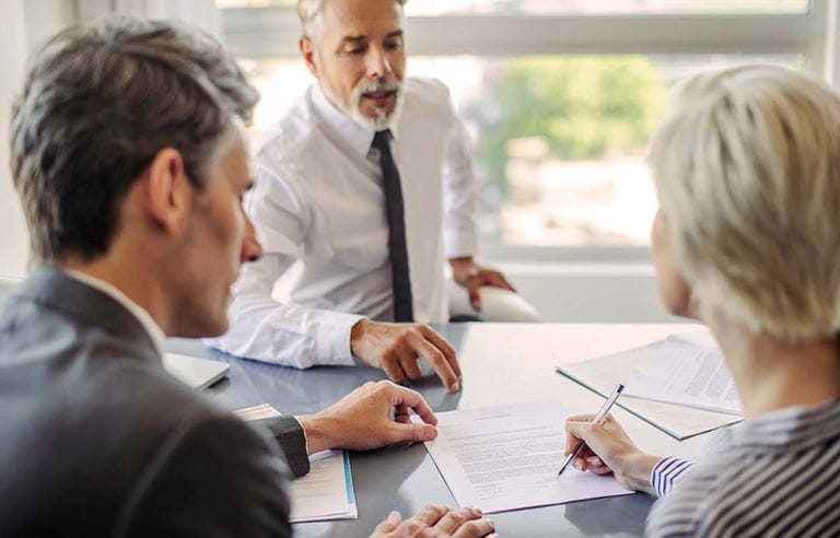 Three people sitting at a table signing papers