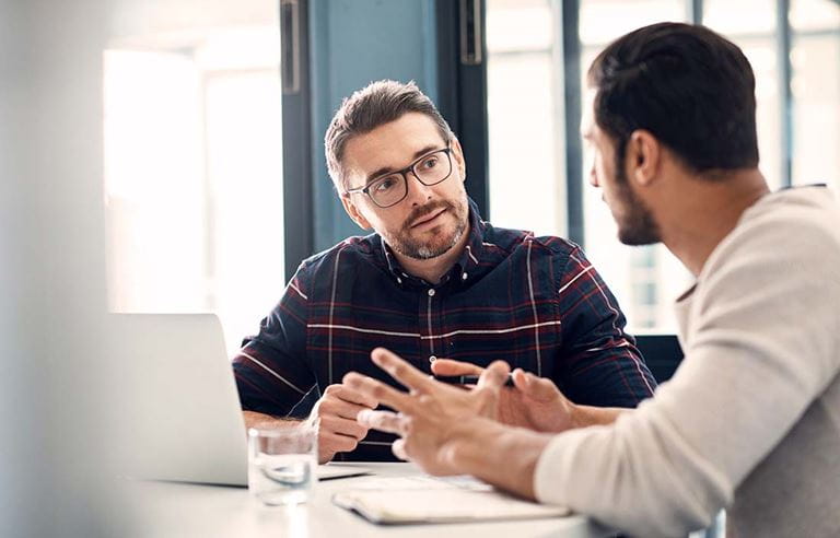 Two men sitting at a table talking