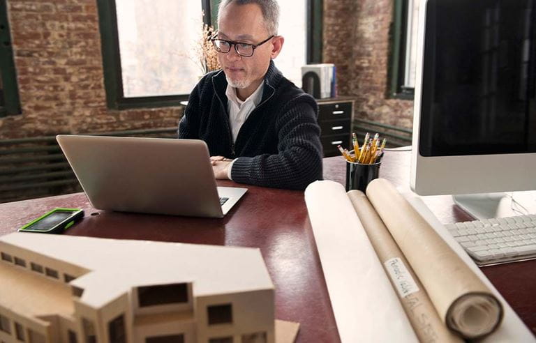 Middle-aged man with glasses looking at his laptop computer screen. 