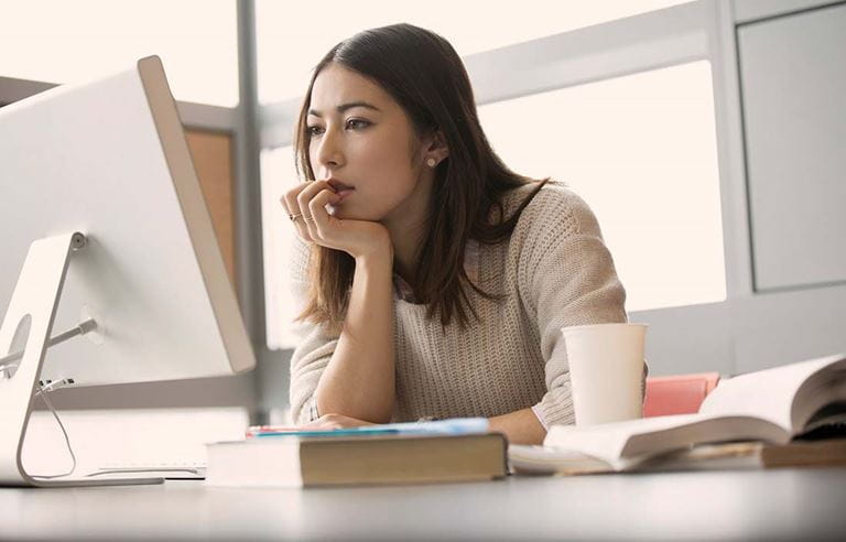 Younger businesswoman using desktop computer and looking intently at the monitor screen.