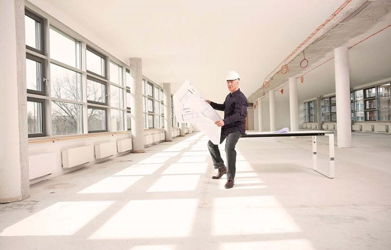 Construction worker/contractor sitting on a table looking at a blueprint.