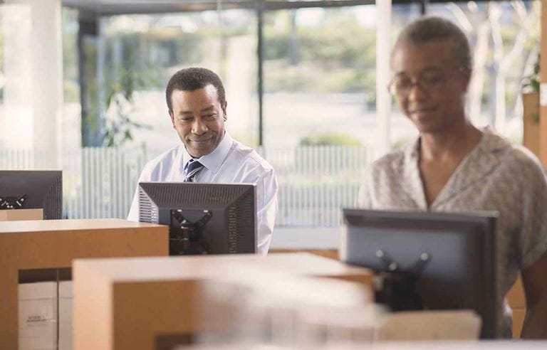 A man and a woman looking at two computer screens