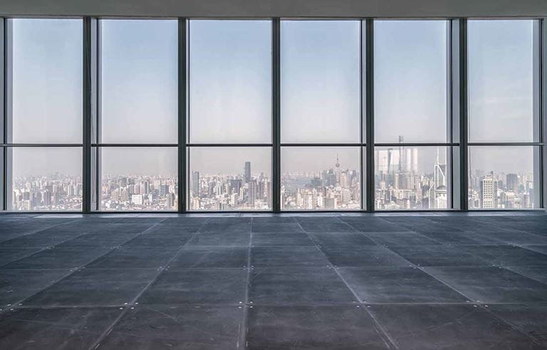 Empty room with floor to ceiling glass windows looking out of a high rise building