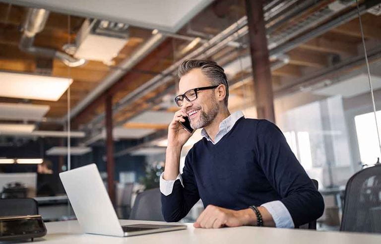 Man sitting at a desk, talking on a phone