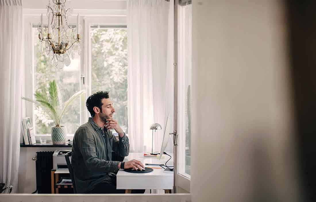 Businessman working at home in casual clothes using his home desktop computer.