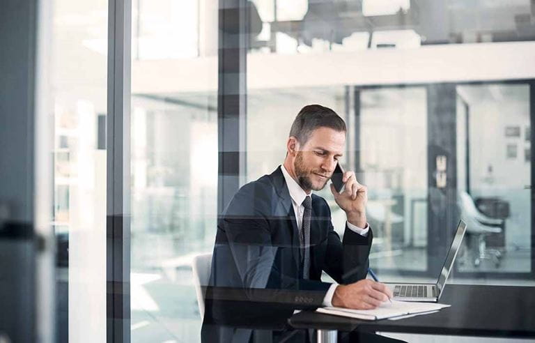 Businessman sitting at a conference table writing on a document.