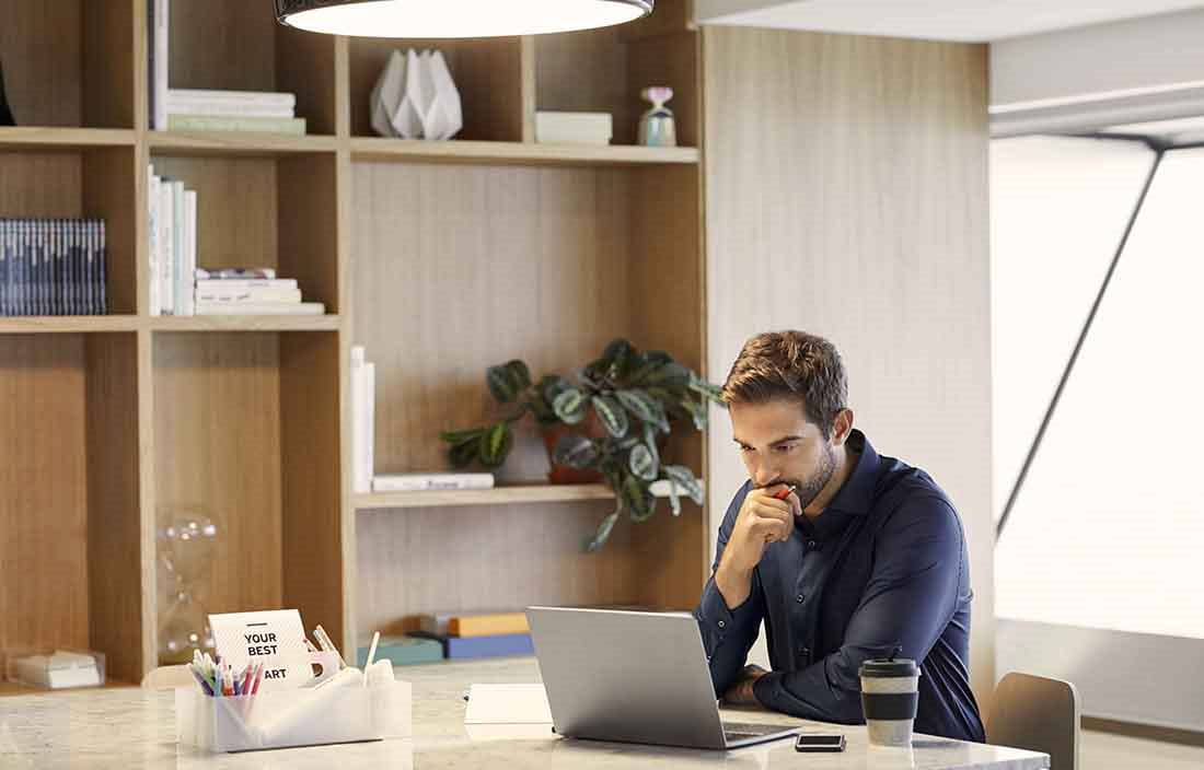 Businessman working from home sitting at his kitchen table using a laptop computer.