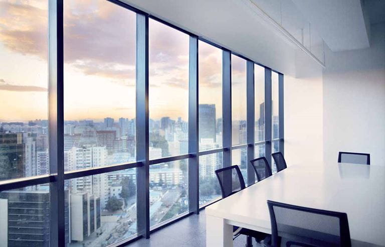 Empty conference room with a view of a city sunset outside the windows.