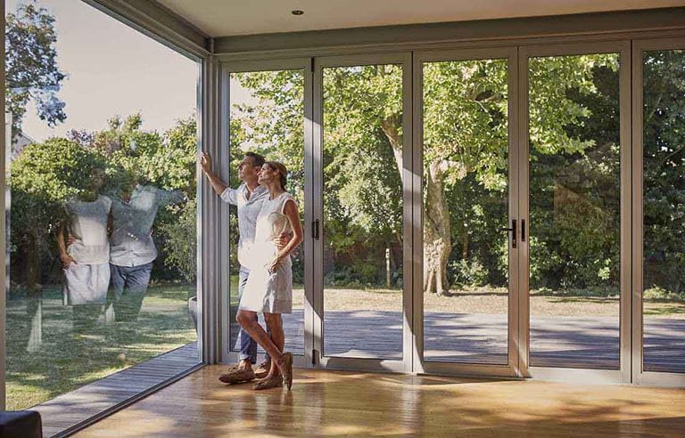 A man and woman looking out their window into the yard.