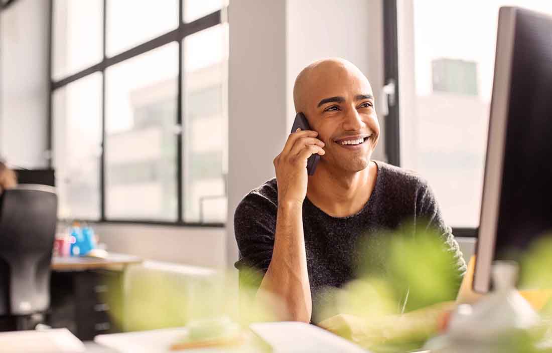 Businessperson taking a phone call on their cell phone smiling.