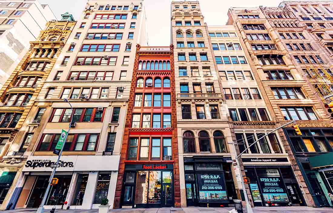 Street-level view of building and shops angled upwards.