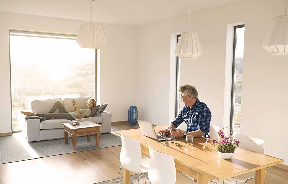 Man working at home in casual clothing using his laptop computer at a kitchen table.