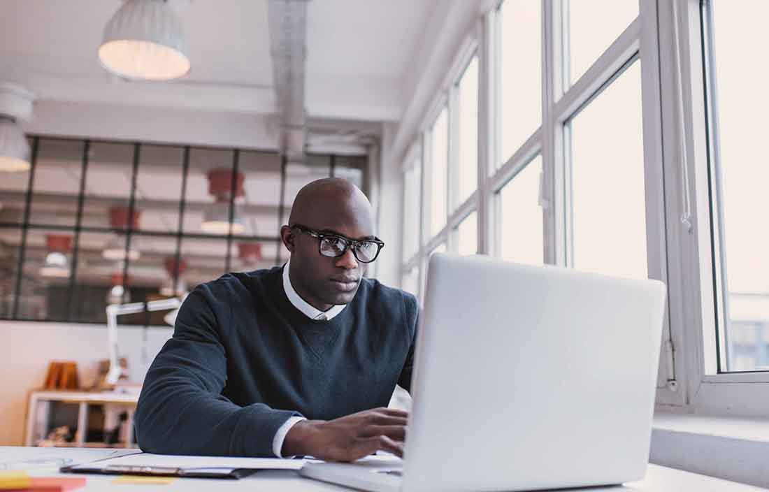 Businessman wearing glasses using a laptop computer.