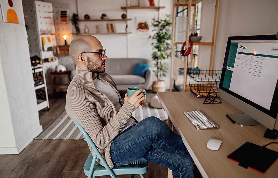 Businessperson having a cup of coffee while viewing their monitor screen.