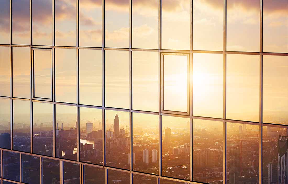 Close-up view of the side of a city skyscraper during sunrise.