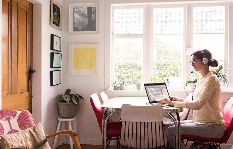 Businesswoman working from home at her kitchen table in casual clothes.