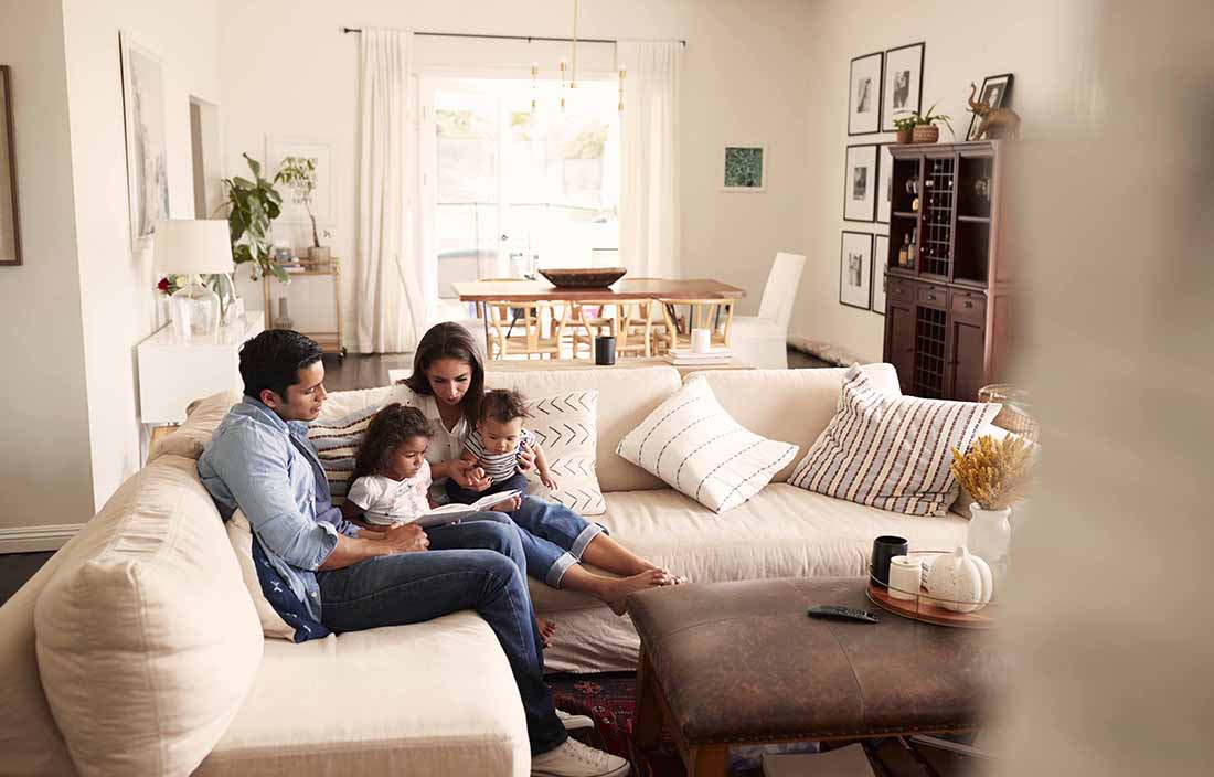 Family sitting in a living room couch together with their two kids.