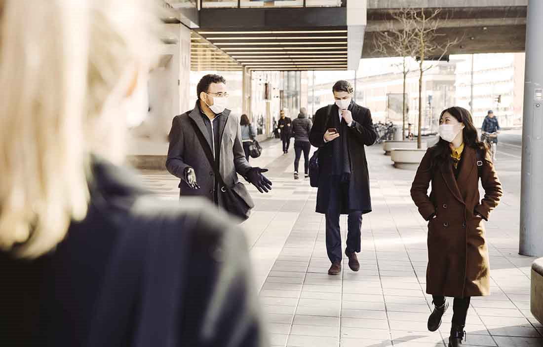 View of pedestrians walking on a city street while wearing protective facemasks.