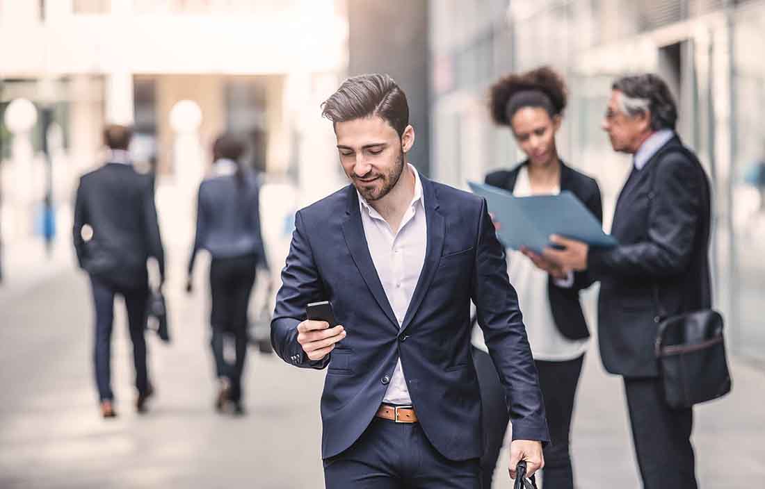 Business professional walking down the street while checking his cellphone.