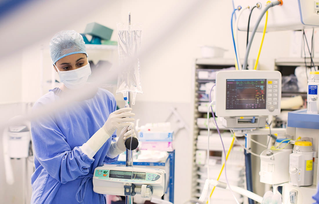 Doctor in scrubs standing next to medical equipment.