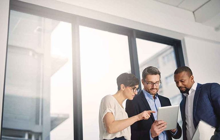 Three business professionals reviewing the NAPIS study on a tablet.