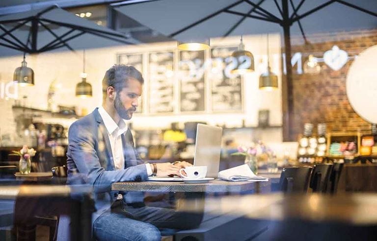 Business professional in a coffee shop using a laptop computer at a table.