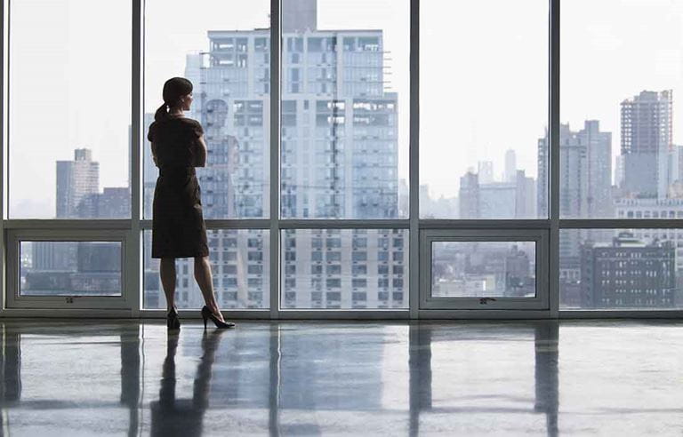 Business professional standing looking out a window.