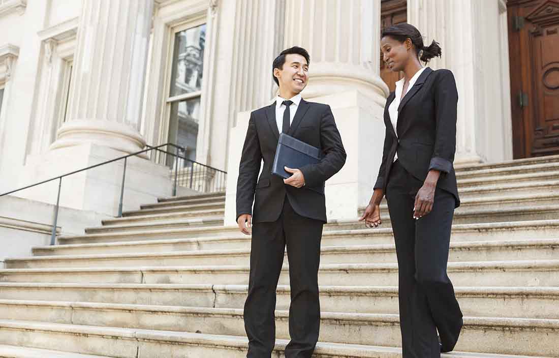 Business professionals walking down a flight of stairs outside a courthouse.