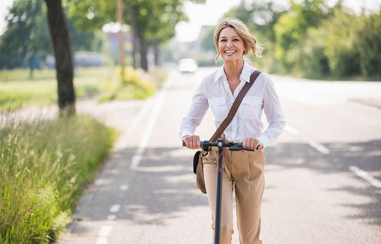 Woman riding an electric scooter down the road.